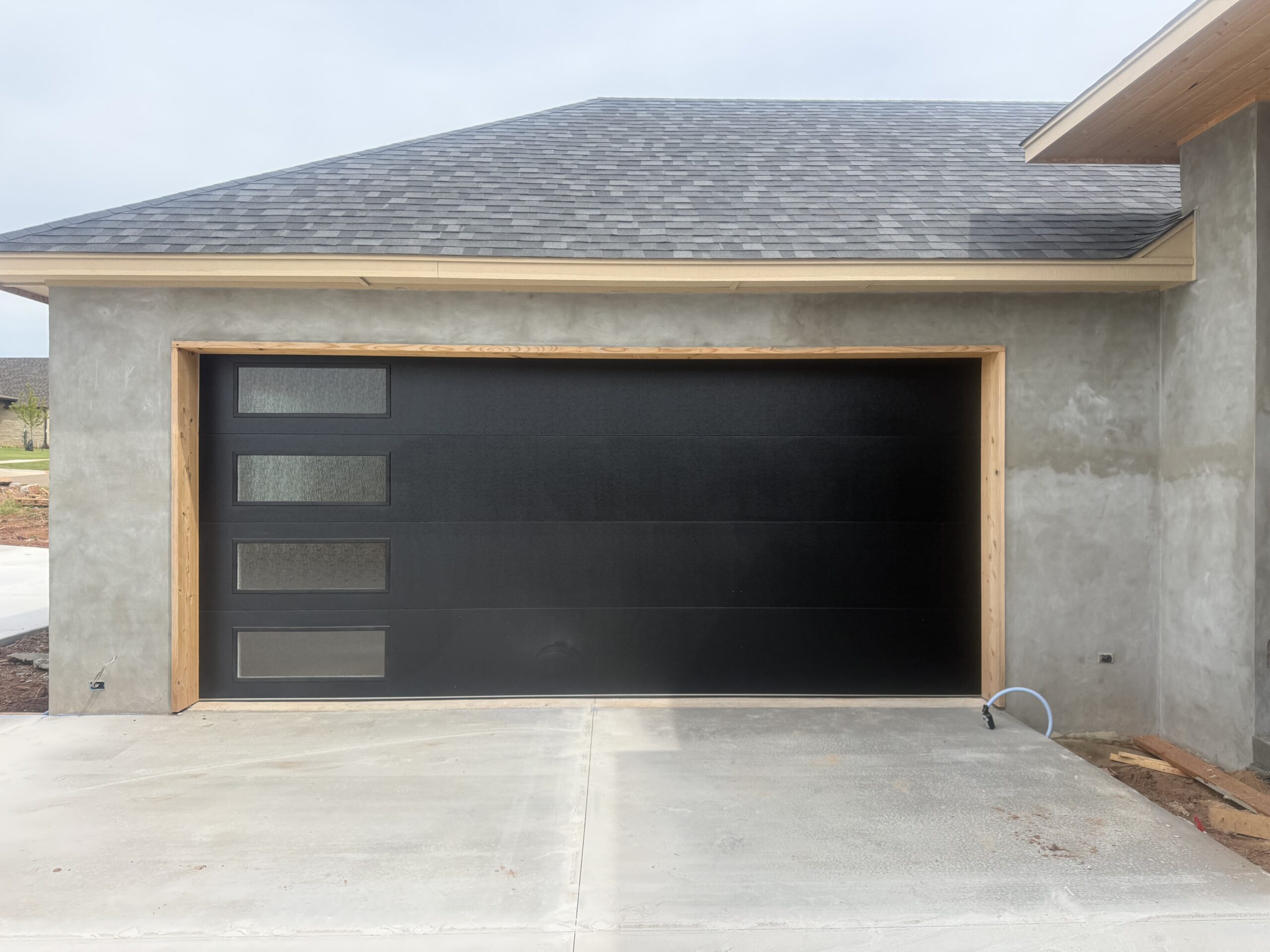 Modern black garage door with vertical frosted-glass windows on a contemporary home